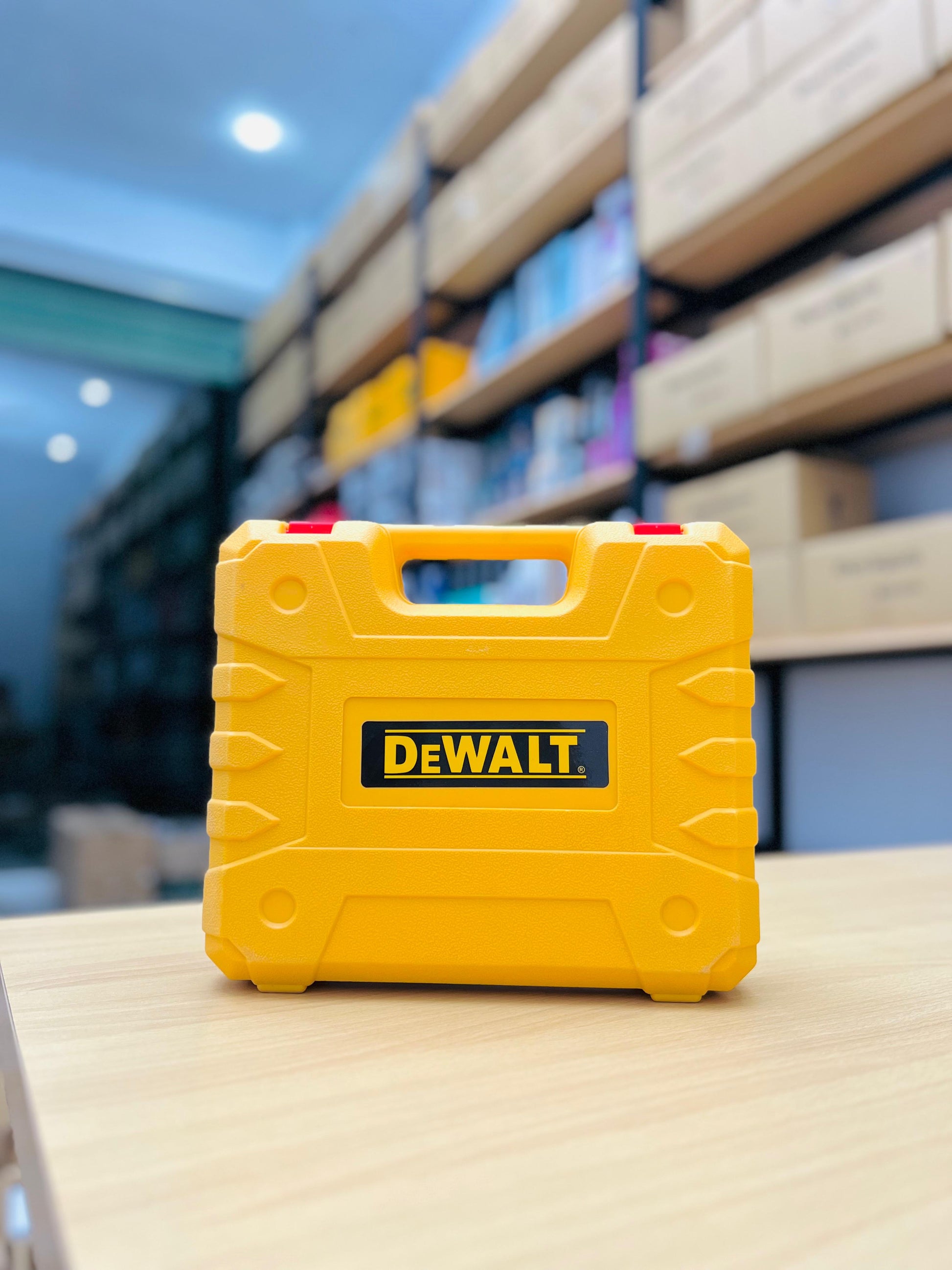 Yellow Dewalt toolbox on a table with shelves in the background