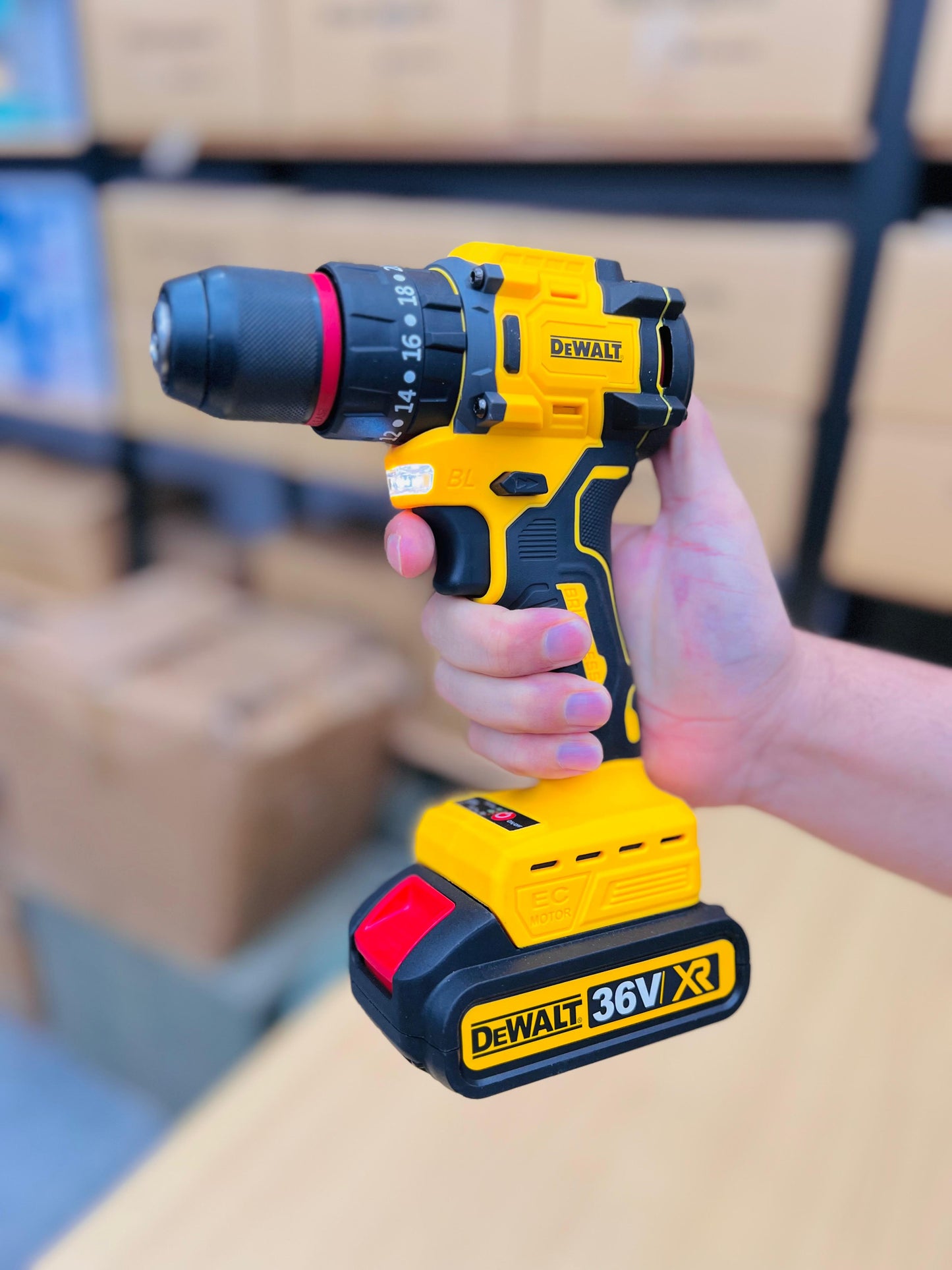 DeWalt cordless drill held by a person with blurred boxes in the background