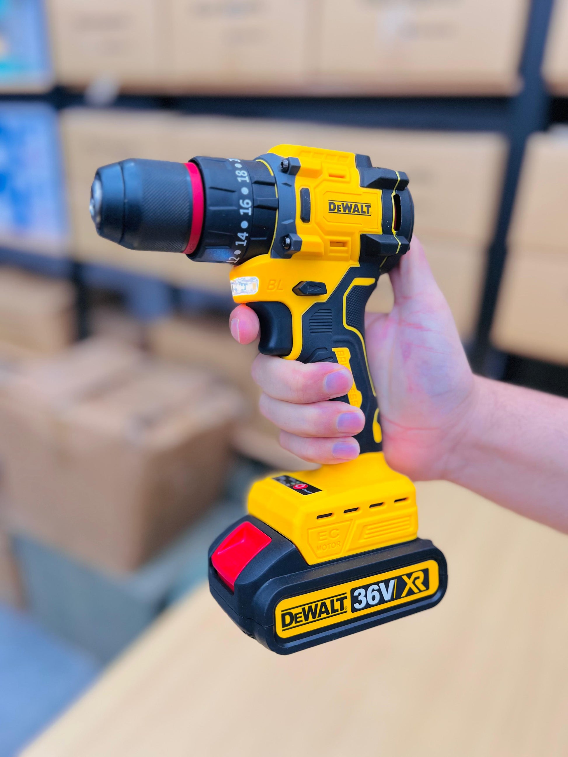 DeWalt cordless drill held by a person with blurred boxes in the background
